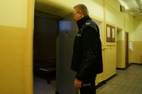 Policjant otworzył drzwi do pomieszczenia dla osób zatrzymanych