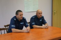 dwóch policjantów siedzi za biurkiem