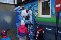 sznupek maluje z dziećmi ścianę budynku