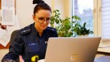 policjantka prowadzi prelekcję onlinę siedząc przed monitorem laptopa