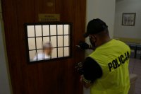 policjant zamyka pomieszczenie dla osób zatrzymanych, w którym znajduje się mężczyzna podejrzany o usiłowanie zabójstwa