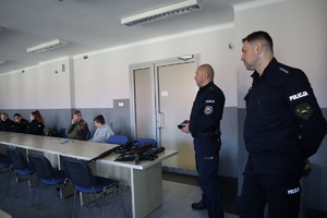 uczniowie klasy mundurowej w sali konferencyjnej KMP w Bytomiu oraz dwaj policjanci w mundurach pokazujący różne rodzaje broni